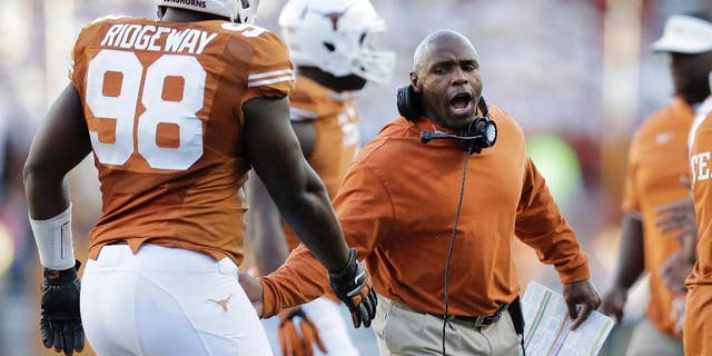 Texas Longhorns head coach Charlie Strong, right, congratulates players as they walk off the field during the second half of an NCAA college football game against West Virginia, Saturday, Nov. 8, 2014, in Austin, Texas. Texas won 33-16. (AP Photo/Eric Gay)