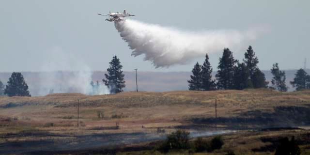 July 20, 2014: A firefighting plane drops water from Fishtrap Lake on a stubborn fire burning near the lake in Lincoln County near Cheney, Wash.  (AP Photo/The Spokesman-Review, Jesse Tinsley)