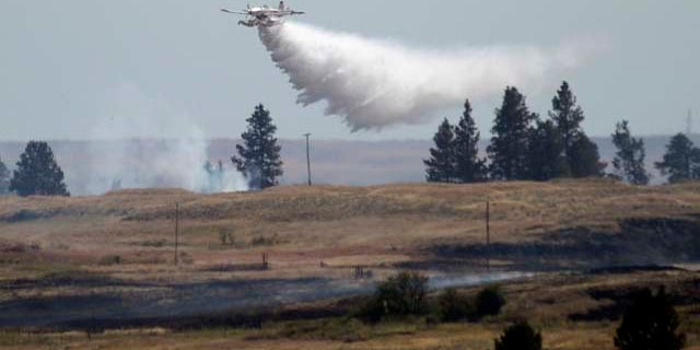 July 20, 2014: A firefighting plane drops water from Fishtrap Lake on a stubborn fire burning near the lake in Lincoln County near Cheney, Wash. (AP Photo/The Spokesman-Review, Jesse Tinsley)