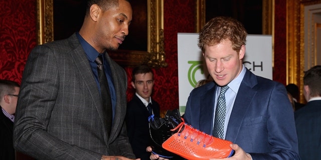 Britain's Prince Harry, right, is presented with a basketball shirt and size 15 basketball shoe by NBA All-Star Carmelo Anthony, during a Coach Core Graduation event at St James's Palace, in London, Wednesday, Jan. 14, 2015. The Coach Core model, a year's apprenticeship, aspires to produce well qualified sports coaches to work in the community. (AP Photo/ Chris Jackson, Pool)