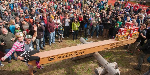 This photo courtesy of Sunday River Communications, Jesse Wall and Christina Arsenault weigh in during the the North American Wife Carrying Championship on Saturday, Oct. 11, 2014, in Newry, Maine. Wall carried Christina Arsenault over a 278-yard course that was bedeviled by log hurdles, sand traps and a "widow maker" water hazard at Sunday River ski resort on Saturday to claim the crown in a time of 1 minute, 4.1 seconds. About 50 couples competed. (AP Photo/Courtesy Sunday River Communications, Nick Lambert)