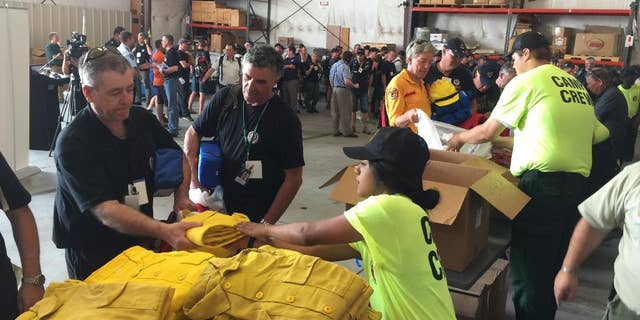 Warren Heslip, 47, of Southland, New Zealand, receives a yellow firefighting shirt on Monday, Aug. 24, 2015 at the National Interagency Fire Center in Boise, Idaho. Australian and New Zealand firefighters have arrived in the United States and prepared to fan out to help fight wildfires burning in several western states. (AP Photo/Keith Ridler)