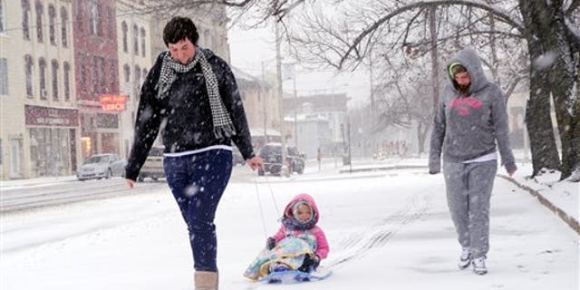 Marissa Birster, right, her little sister, Diamond Devalle, 3, and their friend Dylan Sessions walk along Indepedence Street in Shamokin on a snowy Saturday, Dec. 14, 2013. (AP Photo/The News-Item, Mike Staugaitis)