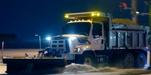 A city plow removes snow from an intersection along 6th Street in Lawrence, Kan., Sunday, March 2, 2014. (AP Photo/Orlin Wagner)