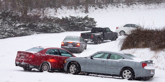 Cars that lost traction sit on the eastbound ramp from Joseph Bryan Boulevard to Holden Road during a snowfall in Greensboro, N.C., Wednesday, Feb. 12, 2014. A major winter slammed into North Carolina Wednesday, turning homebound commutes that typically take minutes into hours-long ordeals as traffic slowed to a slippery slog and threatening to leave many areas dark because of power outages. (AP Photo/News & Record, Nelson Kepley)