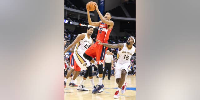 Washington Wizards' Otto Porter (22) , goes up to shoot while defended by New Orleans Pelicans' Alexis Ajinca (42) and John Salmons (15) during the second half of an NBA preseason basketball game in Jacksonville, Fla., Wednesday, Oct. 8, 2014. (AP Photo/Gary McCullough)