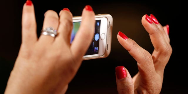 A woman takes a photo as U.S. President Barack Obama holds an event aimed at increasing transparency about women's pay during an event at the White House in Washington April 8, 2014. Obama signed two executive actions, part of a continuing effort by the administration to ensure women are paid equally to their male counterparts for similar work.
REUTERS/Kevin Lamarque (UNITED STATES - Tags: POLITICS BUSINESS EMPLOYMENT) - RTR3KG84