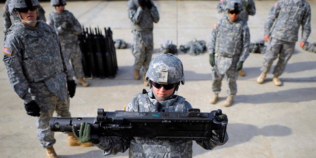 FILE - In this Feb. 23, 2014 file photo, an Army SPC hoists a 44-pound section of a 50 caliber machine gun onto a M1 A2 Abrams tank during a physical demands study at Ft. Stewart, Ga. (AP Photo/Stephen B. Morton, File)