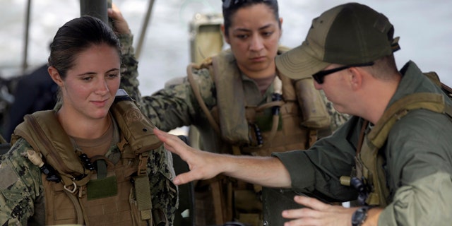 In this Aug. 13, 2013 file photo, U.S. Navy Master-at-Arms Third Class Danielle Hinchliff, left, and Master-at-Arms Third Class Anna Schnatzmeyer, center, participate in a U.S. Navy Riverine Crewman Course under instructor Boatswain's Mate Second Class Christopher Johnson, right, on a Riverine Assault Boat at Camp Lejeune, N.C. (AP Photo/Gerry Broome, File)