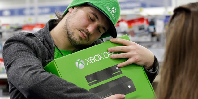 Emanuel Jumatate, from Chicago, hugs his new Xbox One after he purchased it at a Best Buy on Friday, Nov. 22, 2013, in Evanston, Ill. Microsoft is billing the Xbox One, which includes an updated Kinect motion sensor, as an all-in-one entertainment system rather than just a gaming console. (AP Photo/Nam Y. Huh)