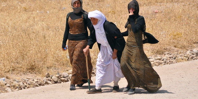 August 5, 2014: Displaced families from the minority Yazidi sect, fleeing the violence, walk on the outskirts of Sinjar, west of Mosul. (REUTERS)