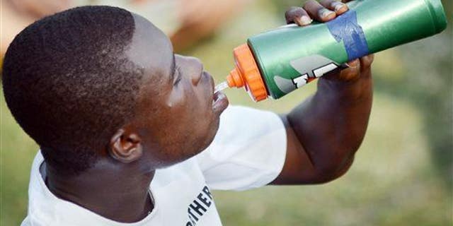 A high school soccer player hydrates during a practice break in the heat.