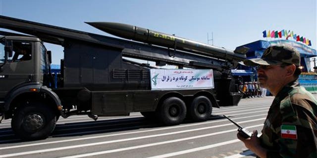 A Zelzal, or earthquake, missile is displayed by the Iranian Revolutionary Guard, as a member of the Guard stands at right, during a military parade marking the 30th anniversary of outset of the 1980-88 Iran-Iraq war, in front of the mausoleum of the late revolutionary founder Ayatollah Khomeini, just outside Tehran, Iran, Wednesday, Sept. 22, 2010.