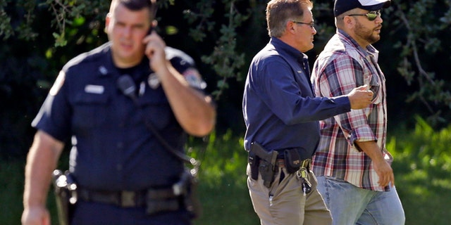 George Zimmerman, right, is escorted to a home by a Lake Mary police officer, center, Monday, Sept. 9, 2013, in Lake Mary, Fla., after a domestic incident in the neighborhood where Zimmerman and his wife Shellie had lived during his murder trial. Zimmerman's wife says on a 911 call that her estranged husband punched her father in the nose, grabbed an iPad out of her hand and smashed it and threatened them both with a gun. Zimmerman was recently found not guilty for the 2012 shooting death of Trayvon Martin. (AP Photo/John Raoux)