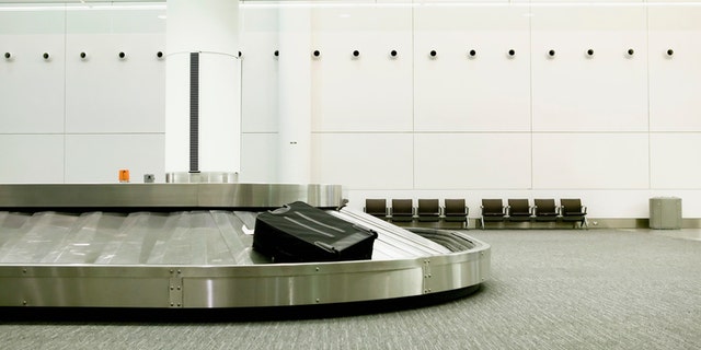 One lonely piece of luggage on an airport carousel.
