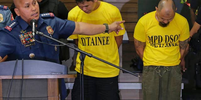 Suspects Jiaher Guinar, center, and Rashid Kilala, right, presented to reporters at police headquarters in Quezon city, north of Manila, Philippines.