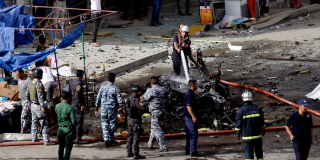 Security forces inspect the scene of a car bomb attack in the Baghdad, Iraq, Monday, May 27, 2013. A parked car bomb explosion in the busy commercial Sadoun Street in central Baghdad, killed and wounded scores of people, police said. (AP Photo/Khalid Mohammed)