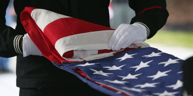 WADING RIVER, NY - DECEMBER 11: A U.S. Navy honor guard folds an American flag after removing it from the casket of Hurricane Sandy victim David Maxwell, before his burial at the Calverton National Cemetery on December 11, 2012 near the Wading River hamlet of Long Island, New York. Maxwell, 66, was the last of Sandy's victims found on the Staten Island borough of New York City, when his body was discovered in his Midland Beach home 11 days after the storm. A Vietnam veteran, he was buried at the national cemetery, accompanied by honor guards from the Catholic War Veterans and the Patriot Guard Riders. (Photo by John Moore/Getty Images)