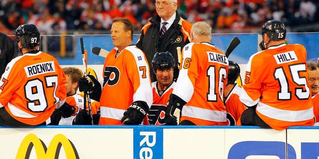 FILE - In this Dec. 31, 2011, file photo, members of the Philadelphia Flyers Alumni team gather on the bench in front of coach Pat Quinn, center, during the Winter Classic Alumni hockey game with the New York Rangers Alumni team in Philadelphia. Quinn, a former defenseman and longtime NHL coach and executive who brought a gruff and passionate presence to hockey across the decades, has died at 71. He died Sunday, Nov. 23, 2014, in Vancouver, British Columbia, after a long illness, the Hockey Hall of Fame and the Western Hockey League's Vancouver Giants said Monday. (AP Photo/Tom Mihalek, File)
