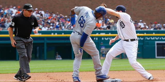 Detroit Tigers third baseman Nick Castellanos shows the ball to third base umpire Paul Schrieber after tagging third base before Los Angeles Dodgers' Yasiel Puig (66) could tag up on a Hanley Ramirez fielders choice in the first inning of a baseball game in Detroit, Wednesday, July 9, 2014. Puig was out on the play. (AP Photo/Paul Sancya)