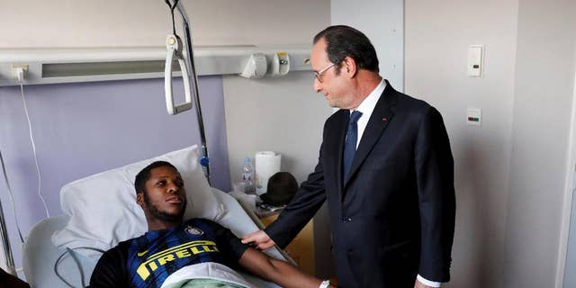 In this photo dated Tuesday, Feb. 7, 2017, provided by Le Parisien, France's President Francois Hollande, right, stands next to alleged victim, identified only by his first name, Theo, at Robert Ballanger hospital in Aulnay-sous-Bois, north of Paris, France. Violence in suburbs northeast of Paris have now spread to at least five towns, erupting after a young black man was allegedly sodomized with a police officer's baton last week, during an identity check. One officer was charged Sunday with aggravated rape and three others were charged with aggravated assault. (Arnaud Journois/Le Parisien via AP)