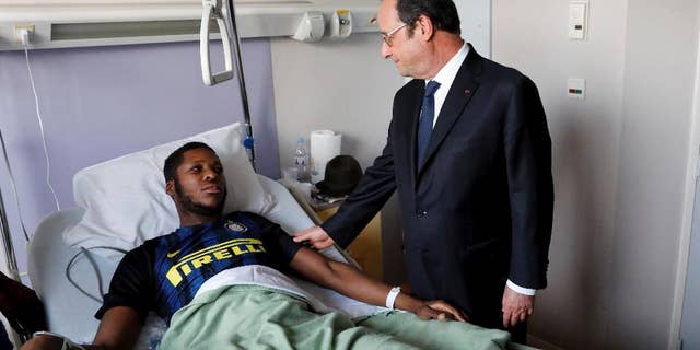 In this photo dated Tuesday, Feb. 7, 2017, provided by Le Parisien, France's President Francois Hollande, right, stands next to alleged victim, identified only by his first name, Theo, at Robert Ballanger hospital in Aulnay-sous-Bois, north of Paris, France. Violence in suburbs northeast of Paris have now spread to at least five towns, erupting after a young black man was allegedly sodomized with a police officer's baton last week, during an identity check. One officer was charged Sunday with aggravated rape and three others were charged with aggravated assault. (Arnaud Journois/Le Parisien via AP)