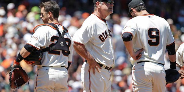 San Francisco Giants manager Bruce Bochy, center, stands on the mound with catcher Buster Posey, left, and first baseman Brandon Belt, right, during a pitching change after the Oakland Athletics scored their sixth run in the sixth inning of their interleague baseball game Thursday, July 10, 2014, in San Francisco. Bochy was relieving relief pitcher Javier Lopez. (AP Photo/Eric Risberg)