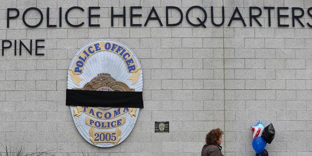 A visitor walks past the growing memorial at police headquarters on Dec. 1, 2016, in memory of Tacoma Police Officer Reginald "Jake" Gutierrez, who was shot and killed while responding to a domestic violence call.