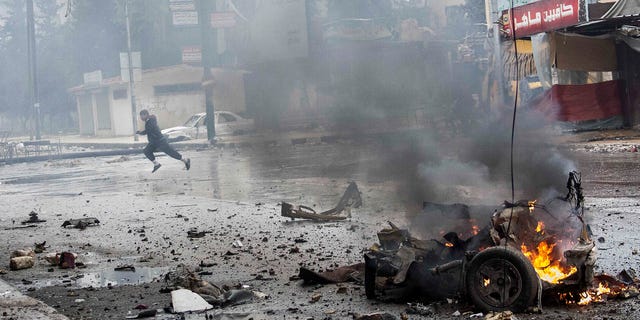 In this Monday, Dec. 17, 2012 photo, a boy runs for cover after a mortar shell hit a street killing several people in the Bustan Al-Qasr district of Aleppo, Syria. (AP Photo/Narciso Contreras)