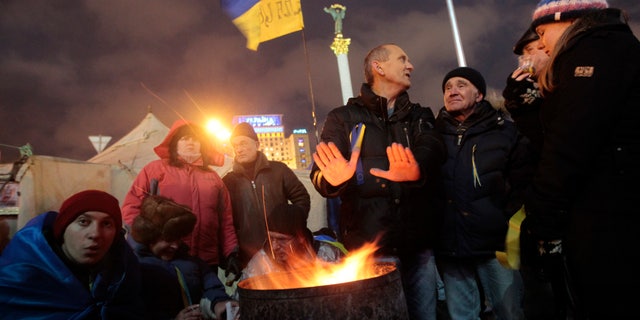 Protesters warm themselves around a fire in Independent Square in Kiev, Ukraine, Saturday, Dec. 7, 2013. As thousands of anti-government protesters kept their vigil in Ukraine's capital Saturday, officials sought to reduce their anger with assurances that Russian and Ukrainian presidents didn’t discuss Ukraine joining a Russian-led customs union at a meeting this week. (AP Photo/Sergei Chuzavkov)
