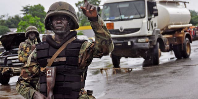 A Liberian soldiers stops people at a security checkpoint setup to lamp down on people traveling due to the Ebola virus, on the outskirts of Monrovia, Liberia, Thursday, Aug. 7, 2014. (AP Photo/Abbas Dulleh)