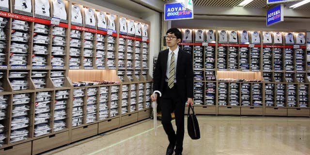 In this June 26, 2015 photo, a man walks past the shelves of shirts in Tokyo. Japan’s economy contracted at a minus 1.2 percent annual rate in the April-June quarter, on higher than earlier estimated inventories and consumer demand. The revised growth figure released Tuesday, Sept. 8, 2015 was better than some economists had anticipated. (AP Photo/Koji Sasahara)