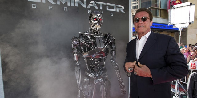 Cast member Arnold Schwarzenegger poses by a Terminator replica at the premiere of 'Terminator Genisys' in Hollywood, California June 28, 2015.