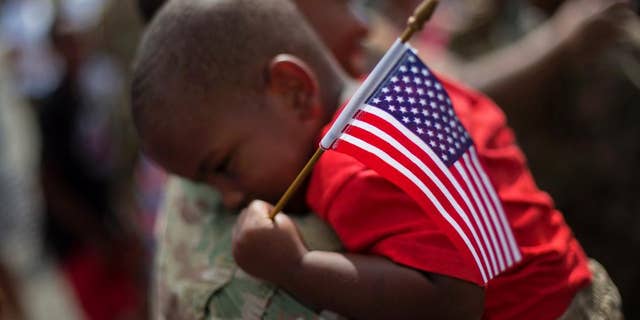 Tyson Hicks, 2, holds an American flag while embraced by his father Sgt. 1st Class Gabriel Hicks upon returning from a deployment to Afghanistan with the Georgia National Guard's 48th Infantry Brigade Combat Team, Tuesday, Sept. 16, 2014, in Macon, Ga. Two hundred Guardsmen returned home Tuesday from a nine-month deployment where they provided security and facilitated the transfers of U.S. military installations to their Afghan counterparts. (AP Photo/David Goldman)