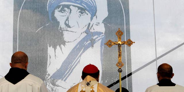 FILE – A portrait of Mother Teresa is pictured behind a crucifix, during a holy Mass dedicated to her on the main square in Skopje, Macedonia, Sunday, Sept 11, 2016. Hundreds of people gathered Sunday at the main square in Macedonian capital Skopje for a ceremony of gratitude dedicated to Mother Teresa who Pope Francis has declared a saint last week in Vatican.