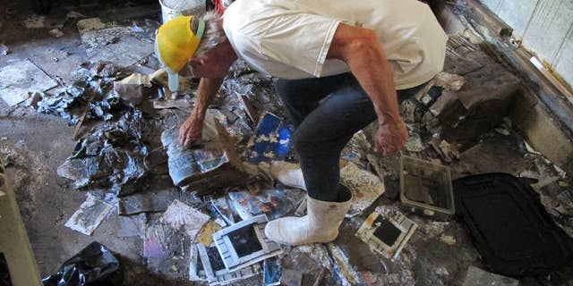 In this Oct. 12, 2016 photo, Walter Coker surveys the damage in his furniture storage shed in Crescent Beach, Fla. Coker runs Genung's Fish Camp and Marina on the shore of the Matanzas River, and saw storm surge from Hurricane Matthew run "like a river" through his property, tearing apart the storage shed and the tackle shop. He doesn't have flood insurance because he said it was too expensive, so is hoping to rebound with the help of neighbors and the community. (AP Photo/Jason H. Dearen)