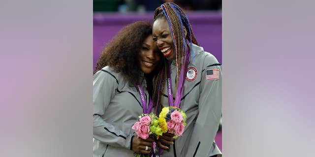 Serena Williams (left) and Venus Williams of the United States celebrate on the podium after winning the women's doubles gold medal in London.