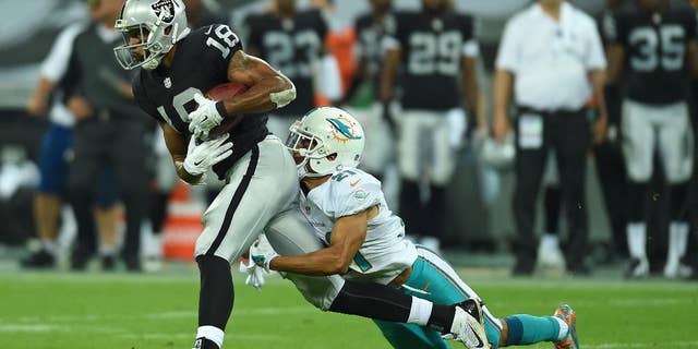 Oakland Raiders' Andre Holmes is tackled by Miami Dolphins' Brent Grimes during the NFL football game at Wembley Stadium in London, Sunday, Sept. 28, 2014. (AP Photo/Tim Ireland)
