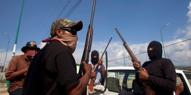 Jan. 18, 2013: In this photo, masked and armed men sit in the back of a pick-up truck at the entrance to the town of Ayutla, Mexico.  Hundreds of  men in the southern Mexico state of Guerrero have taken up arms to defend their villages against drug gangs, a vigilante movement born of frustration at extortion, killings and kidnappings in a region wracked by violence.