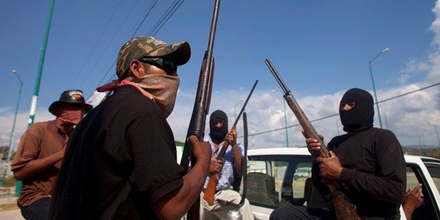 Jan. 18, 2013: In this photo, masked and armed men sit in the back of a pick-up truck at the entrance to the town of Ayutla, Mexico. Hundreds of men in the southern Mexico state of Guerrero have taken up arms to defend their villages against drug gangs, a vigilante movement born of frustration at extortion, killings and kidnappings in a region wracked by violence.