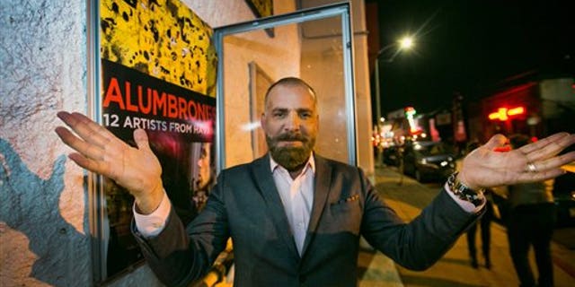 Cuban producer Fermin Rojas poses with the poster of his film, "Alumbrones" in Los Angeles.