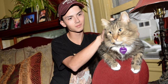 FILE - In a Wednesday, Sept. 10, 2014 file photo, Draven Rodriguez and his cat Mr. Bigglesworth at their home in Schenectady, N.Y. Rodriguezâs parents tell the Times-Union of Albany their son committed suicide Thursday, Feb. 19, 2015 at their Schenectady home. He was 17. Rodriguez had wanted his senior yearbook portrait to show him holding his cat Mr. Bigglesworth, with lasers in the background. The school denied his request but said the photo could appear somewhere in the Schenectady High School yearbook.(AP Photo/The Daily Gazette, Patrick Dodson)