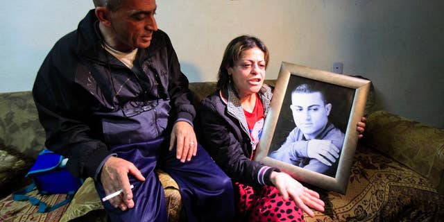 March 10, 2015: Hind, the mother of Muhammad Said Ismail Musallam, holds a picture of her son as she speaks to the Associated Press while seated next to her husband Said Musallam at their home.