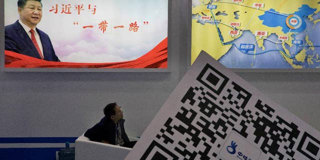 A conference attendee listens at a portrait of China's President Xi Jinping looms in the background, April 28, 2017.