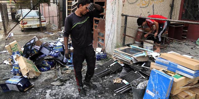 Iraqis clean up the site of a car bomb near restaurants and shop in Palestine Street in eastern Baghdad, Iraq, Wednesday, June 10, 2015. On Tuesday night, a series of bombings targeting public places and Iraqi security forces killing and wounding civilians. (AP Photo/Karim Kadim)