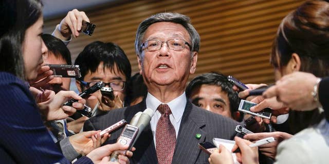 FILE - In this March 4, 2016 file photo, Okinawa Gov. Takeshi Onaga is surrounded by reporters after a meeting with Japanese Prime Minister Shinzo Abe at the latter's official residence in Tokyo.  Japan and the U.S. have marked a partial return of the land used by American troops to Okinawa in a ceremony on the southern island Thursday, Dec. 22, 2016, , but there was no sign the move was helping to lessen protests against the heavy U.S. military presence. Demanding an unconditional land return, Okinawa Gov. Onaga skipped Thursday’s ceremony and joined a protest. (Kimimasa Mayama/Pool Photo via AP, File)