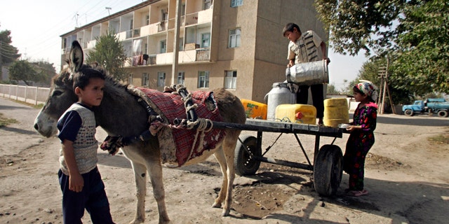 FILE - In this Friday Nov. 3, 2006 file photo, children gather water from a open canal in the town of Dosti, in southern Tajikistan. While the Tajik economy has gradually recovered to its Soviet-era level and has been growing over the past few years, the country remains one of the poorest nations in the former Soviet Union. Tajikistan is holding a presidential election on Wednesday, Nov. 6, 2013.
