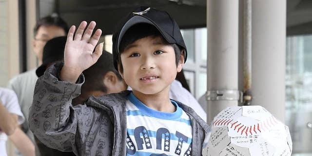 FILE - In this June 7, 2016 file photo, Yamato Tanooka, who survived almost a week in a forest after his parents left him at the side of a road,  waves as he leaves a hospital in Hakodate on the northern island of Hokkaido. The Japanese boy was released from a hospital this week, smiling and waving at a crowd cheering the happy ending. Public criticism of the father, who made 7-year-old Tanooka get out of the car to punish him for misbehavior, has faded, and police reportedly won’t pursue charges. (Daisuke Suzuki/Kyodo News via AP, File) JAPAN OUT, MANDATORY CREDIT