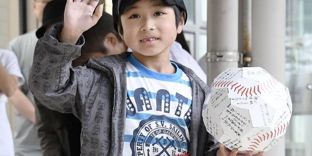 FILE - In this June 7, 2016 file photo, Yamato Tanooka, who survived almost a week in a forest after his parents left him at the side of a road, waves as he leaves a hospital in Hakodate on the northern island of Hokkaido. The Japanese boy was released from a hospital this week, smiling and waving at a crowd cheering the happy ending. Public criticism of the father, who made 7-year-old Tanooka get out of the car to punish him for misbehavior, has faded, and police reportedly won’t pursue charges. (Daisuke Suzuki/Kyodo News via AP, File) JAPAN OUT, MANDATORY CREDIT
