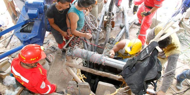 Miners and rescue workers work at the entrance to the El Tunel gold mine in Riosucio, Colombia, Wednesday, May 13, 2015. Fifteen miners are missing and feared dead after water poured into the underground shafts where they were digging early Wednesday. Authorities said the accident was likely triggered by an explosion or power outage that disabled pumps used to extract water and supply oxygen to work crews. (AP Photo/Juan Augusto Cardona)